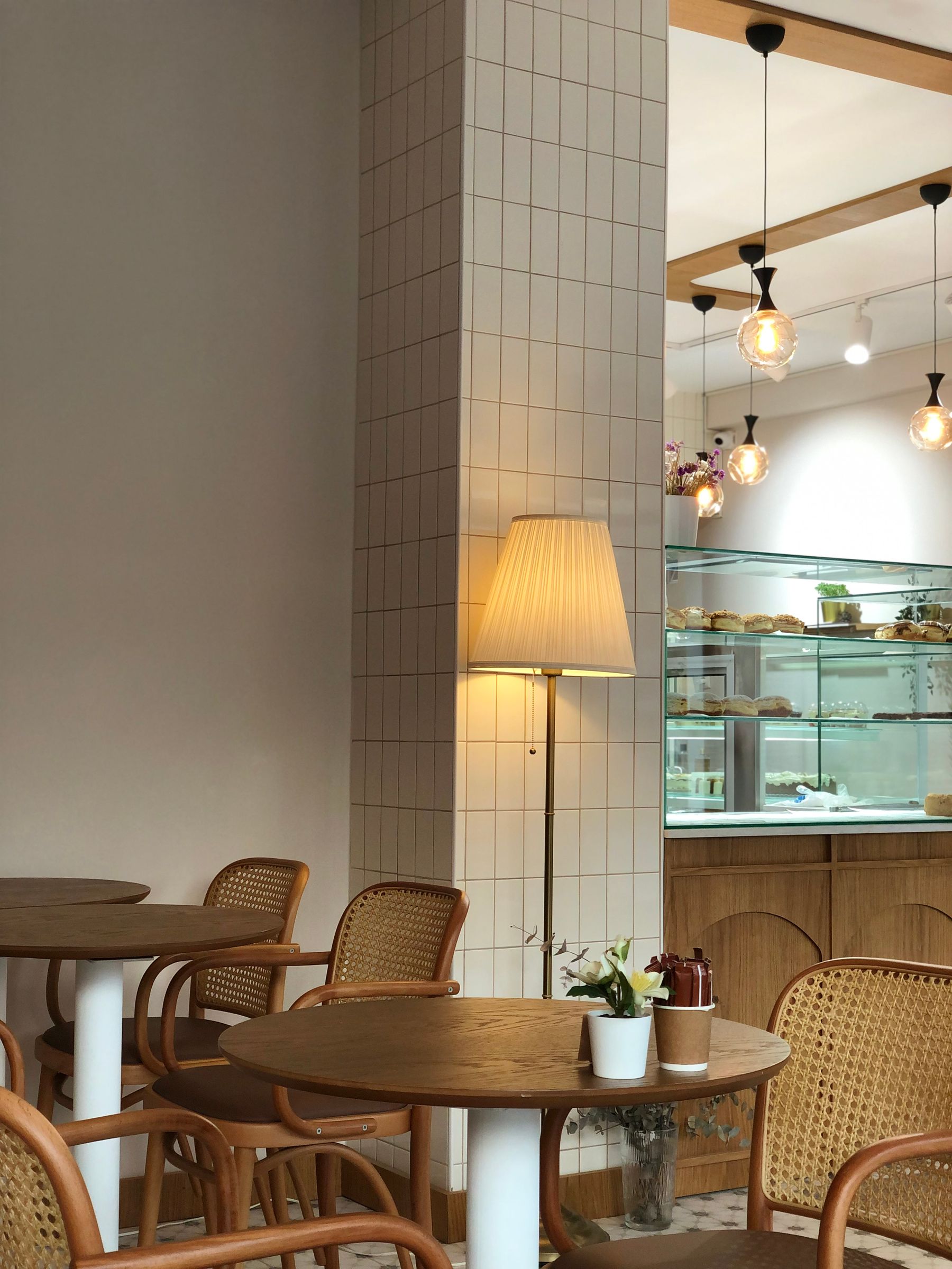 Interior kafe hangat dengan furnitur kayu dan area duduk dekat jendela